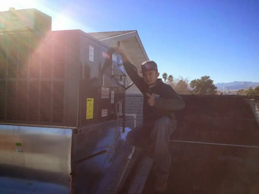 HVAC technician performing Air Duct Cleaning on a rooftop unit in Carlyss